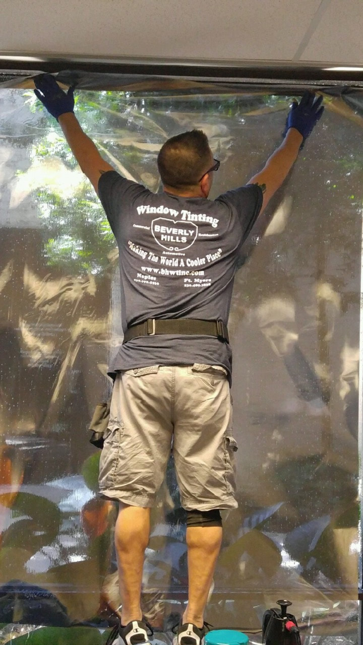 Paul Russo installing window film at Naples City Hall